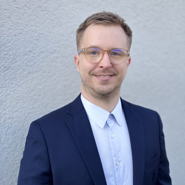 Sebastian Wolz, Bauingenieur Sympathisch lächelnder junger Mann im blauen Anzug mit Brille, Sebastian Wolz, Bauingenieur, Baubegleitung, -begutachtung